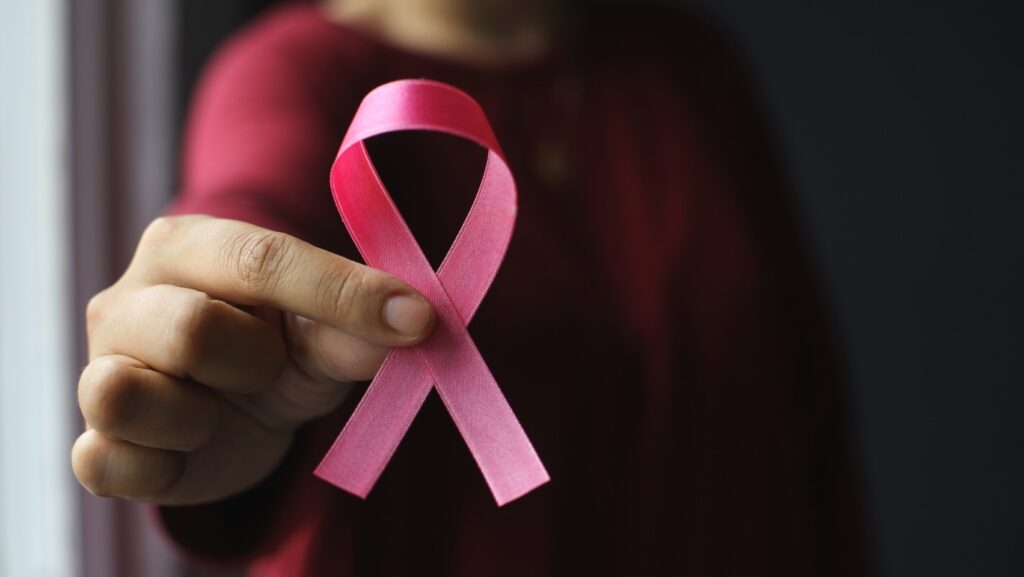Pink breast cancer awareness ribbon on a black background.