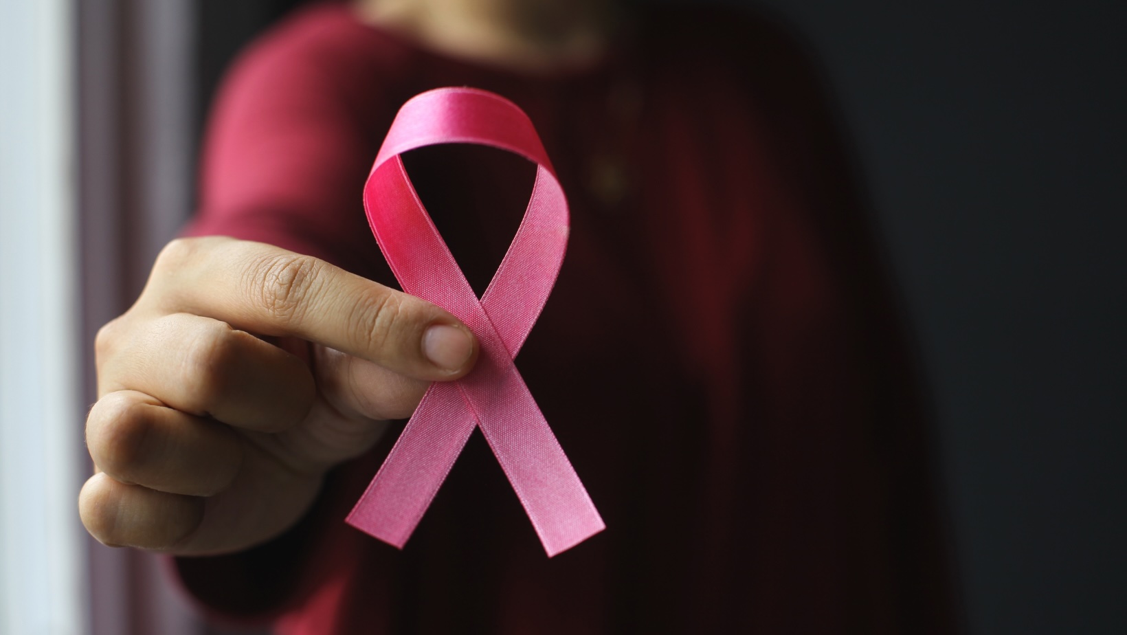 Pink breast cancer awareness ribbon on a black background.